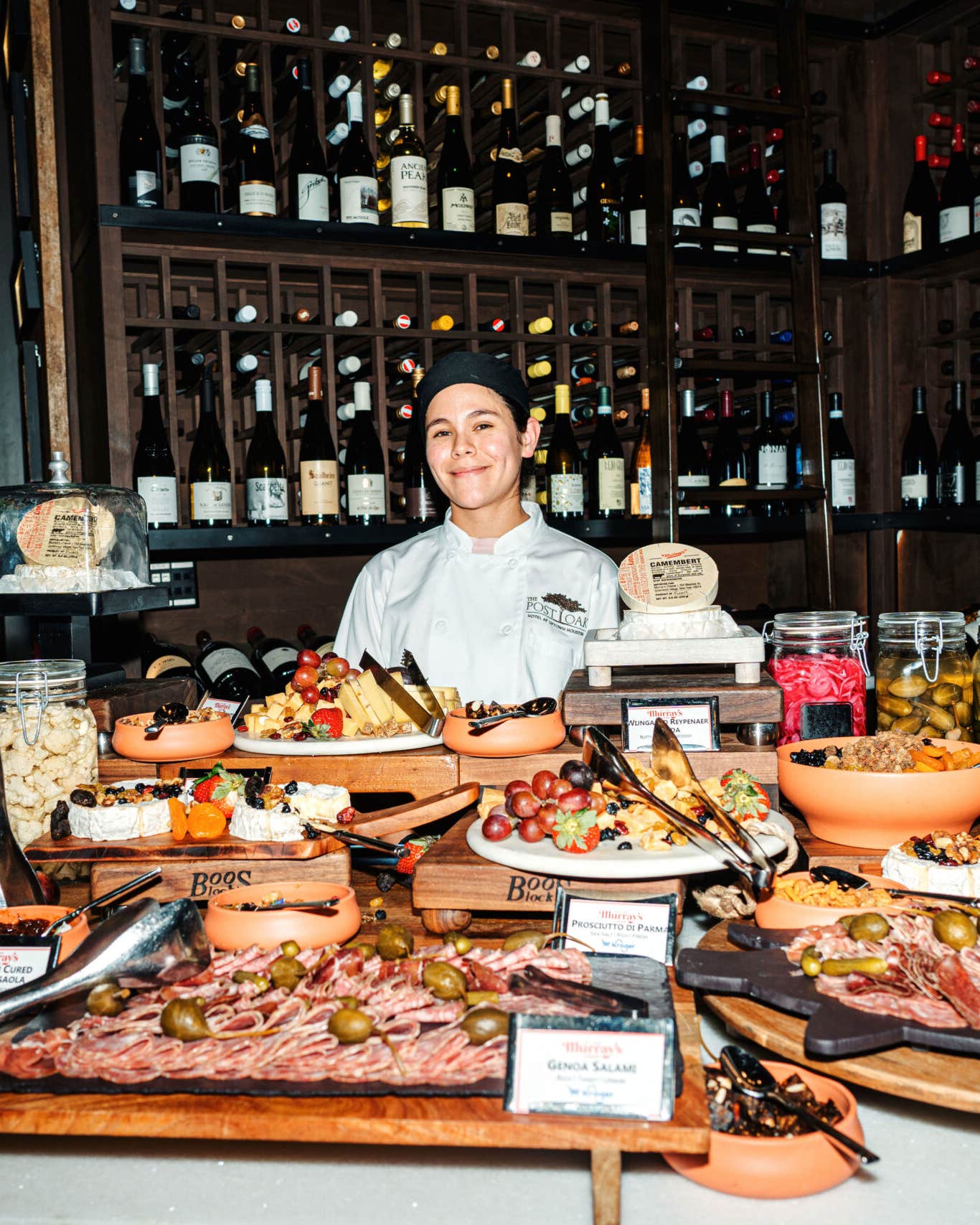 A chef stands behind an extravagant cheese and charcuterie grazing table in Stella's Wine Bar.